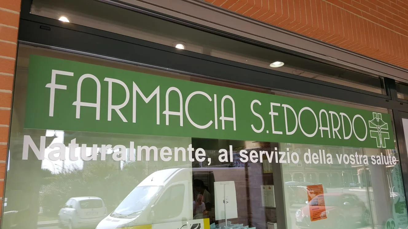 Vetrofania verde con il nome della farmacia e scritta bianca sulla vetrina