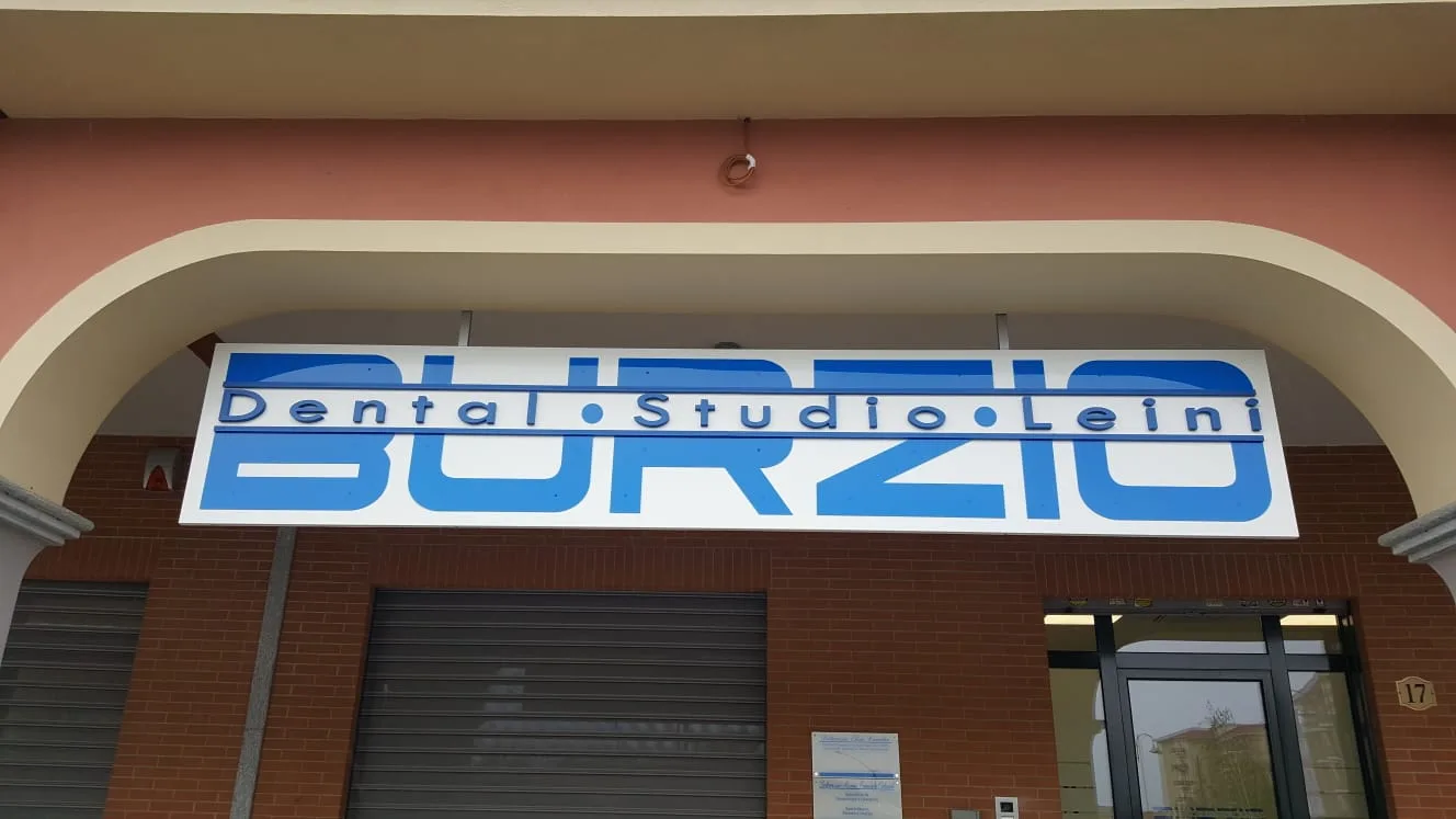 Insegna bianca con lettere blu in rilievo sotto il portico di uno studio dentistico