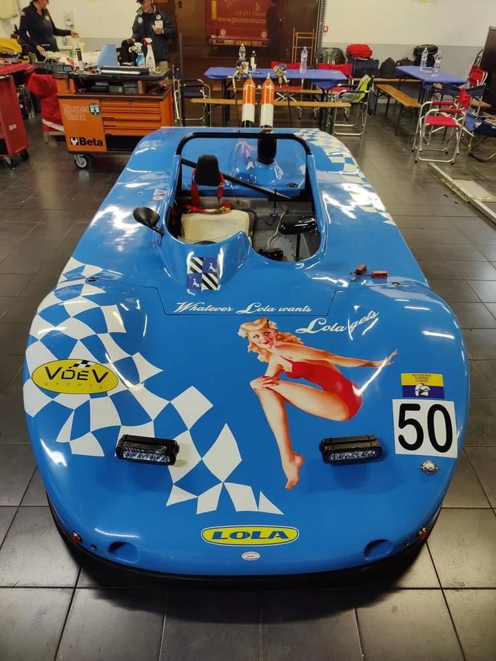 Auto da corsa d'epoca azzurra decorata con bandiera a scacchi, numero di gara e illustrazione pin-up