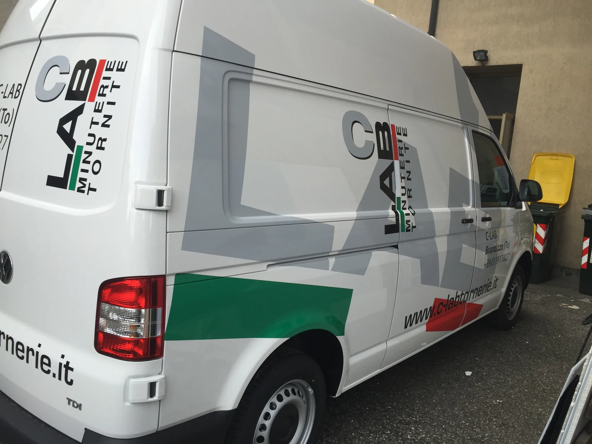 Furgone bianco allestito con grafica in prespaziato grigia, rossa e verde e il logo dell'azienda