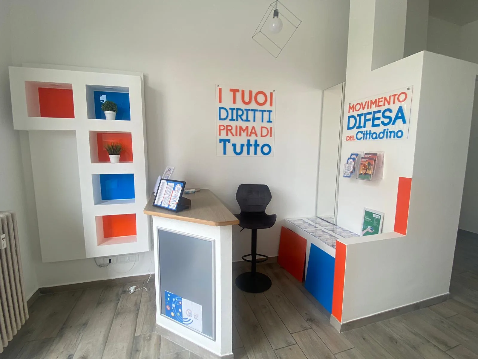 Ufficio allestito con pannelli in plexiglass a parete con scritte blu e arancioni e inserti colorati nelle nicchie