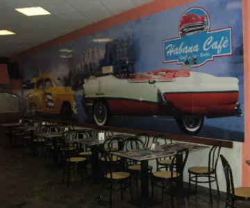 Locale con grande grafica da parete di auto d'epoca e insegna Habana Café