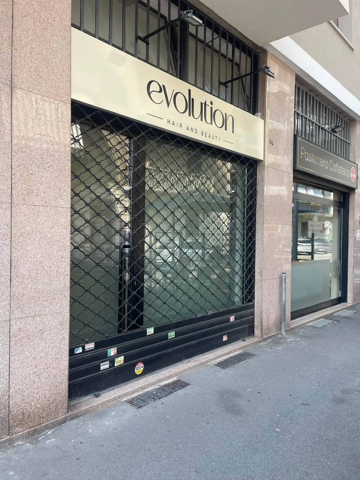 Insegna color crema con scritta nera sopra la vetrina di un salone