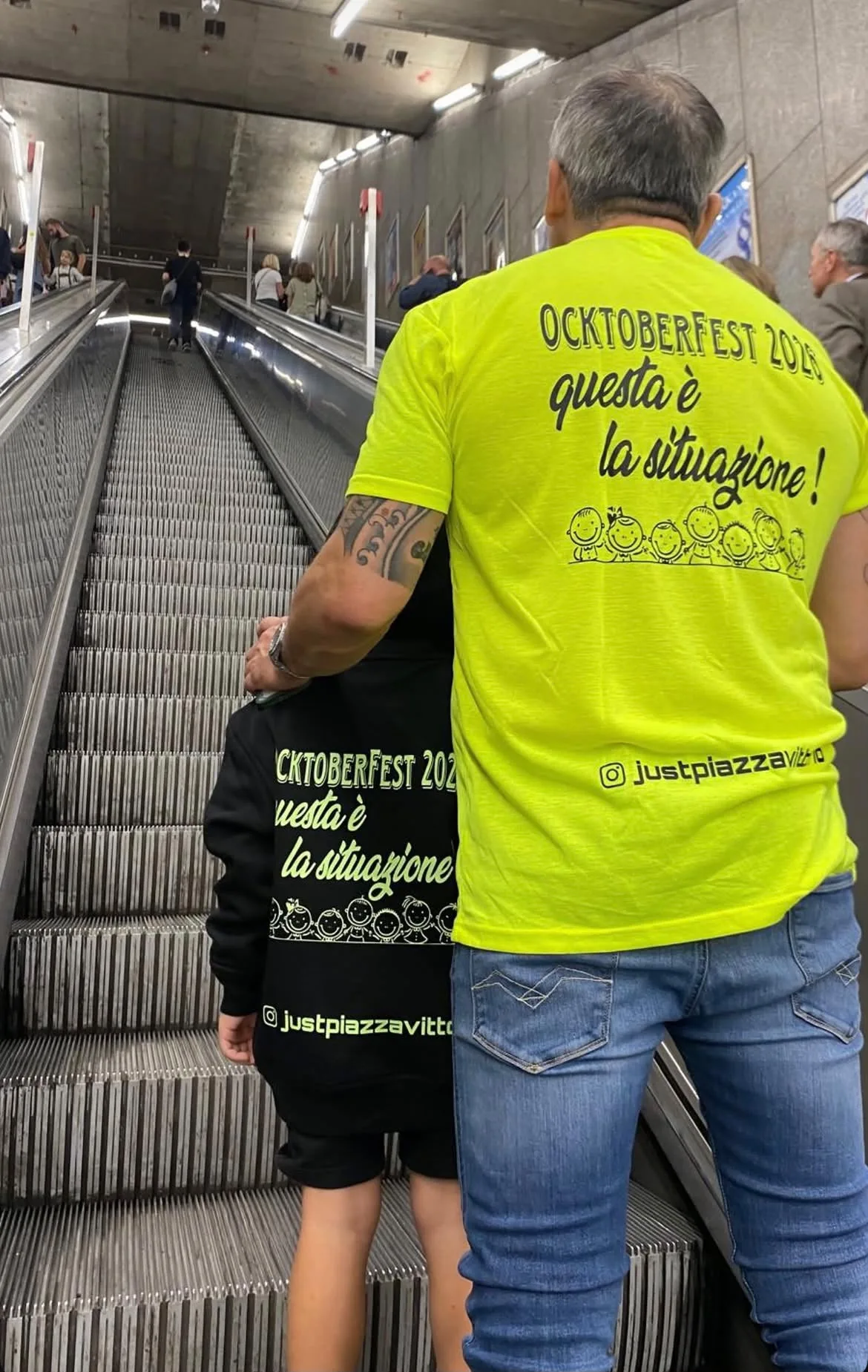 T-shirt gialla fluo e felpa nera stampate per un evento, indossate in metropolitana