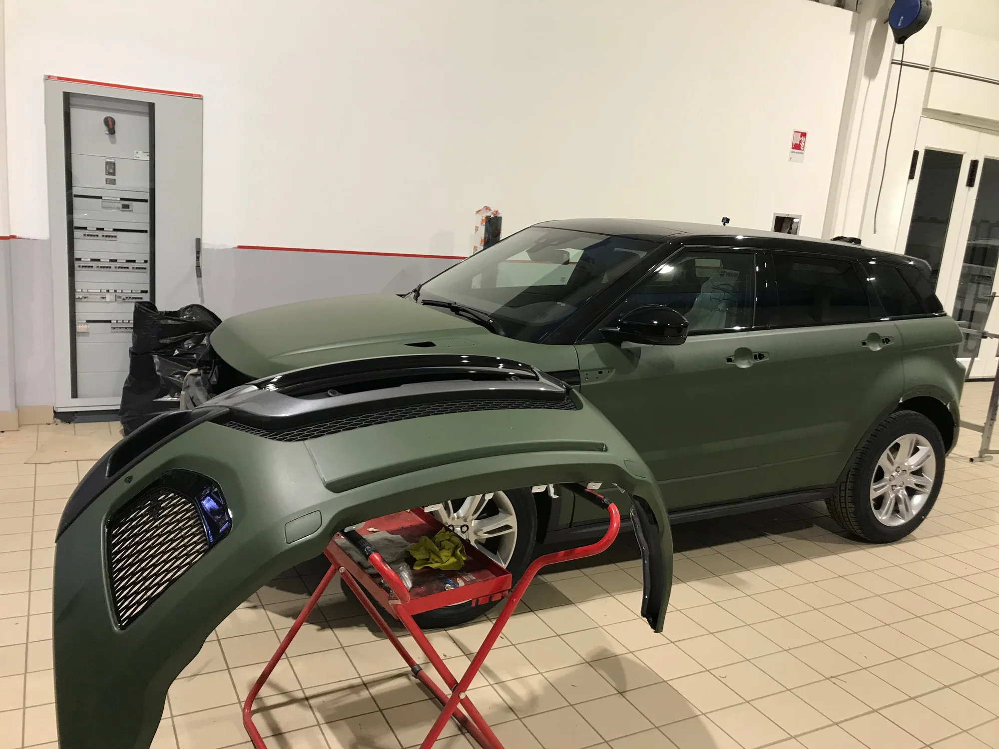 Suv rivestito con pellicola verde opaco in laboratorio, con il paraurti pronto da montare