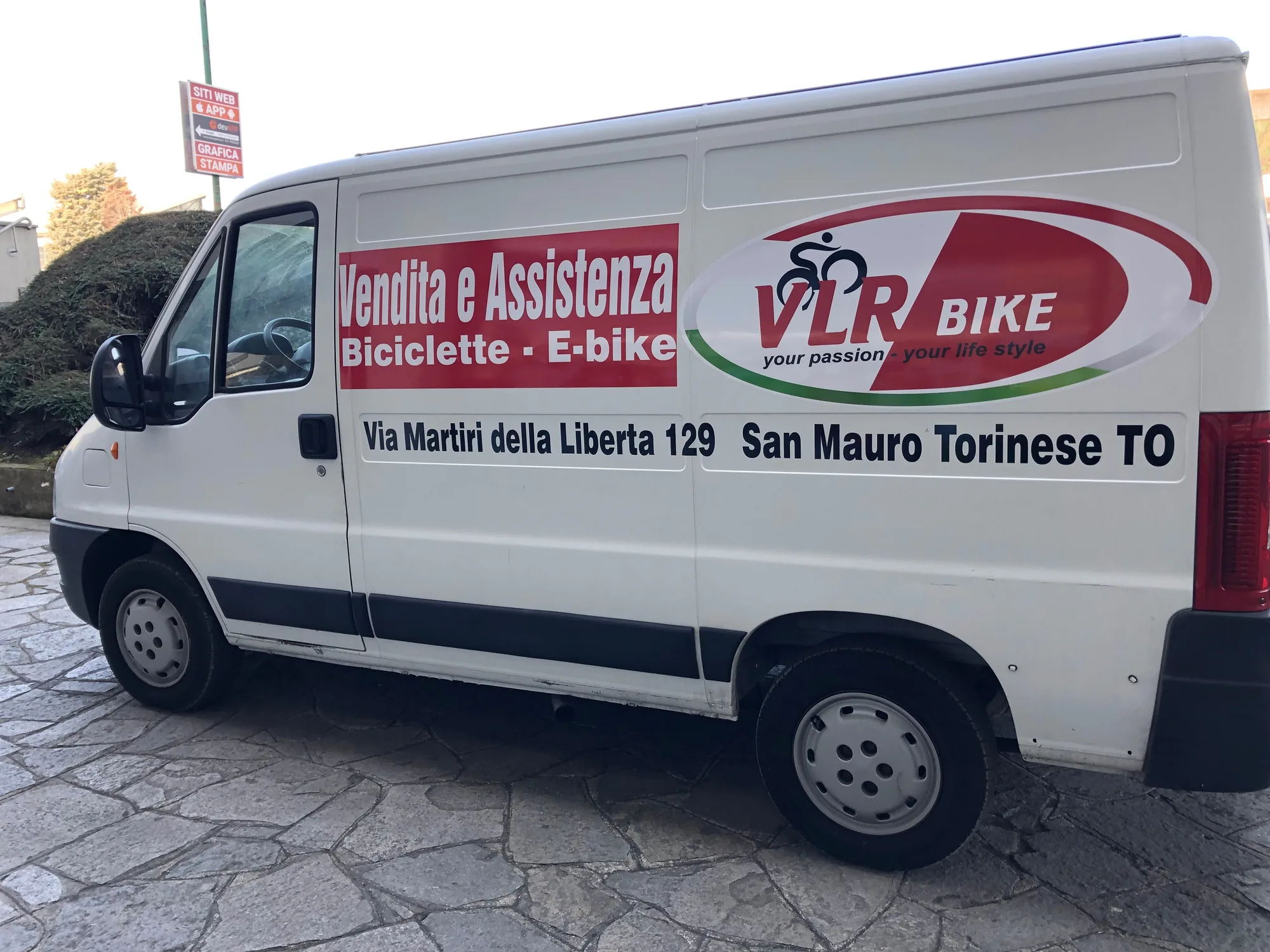 Furgone di un negozio di biciclette con scritte, logo e indirizzo sulla fiancata
