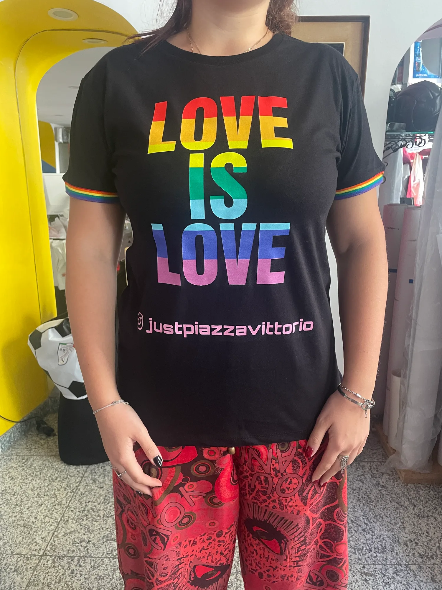T-shirt nera con la scritta Love is love stampata a colori arcobaleno, indossata