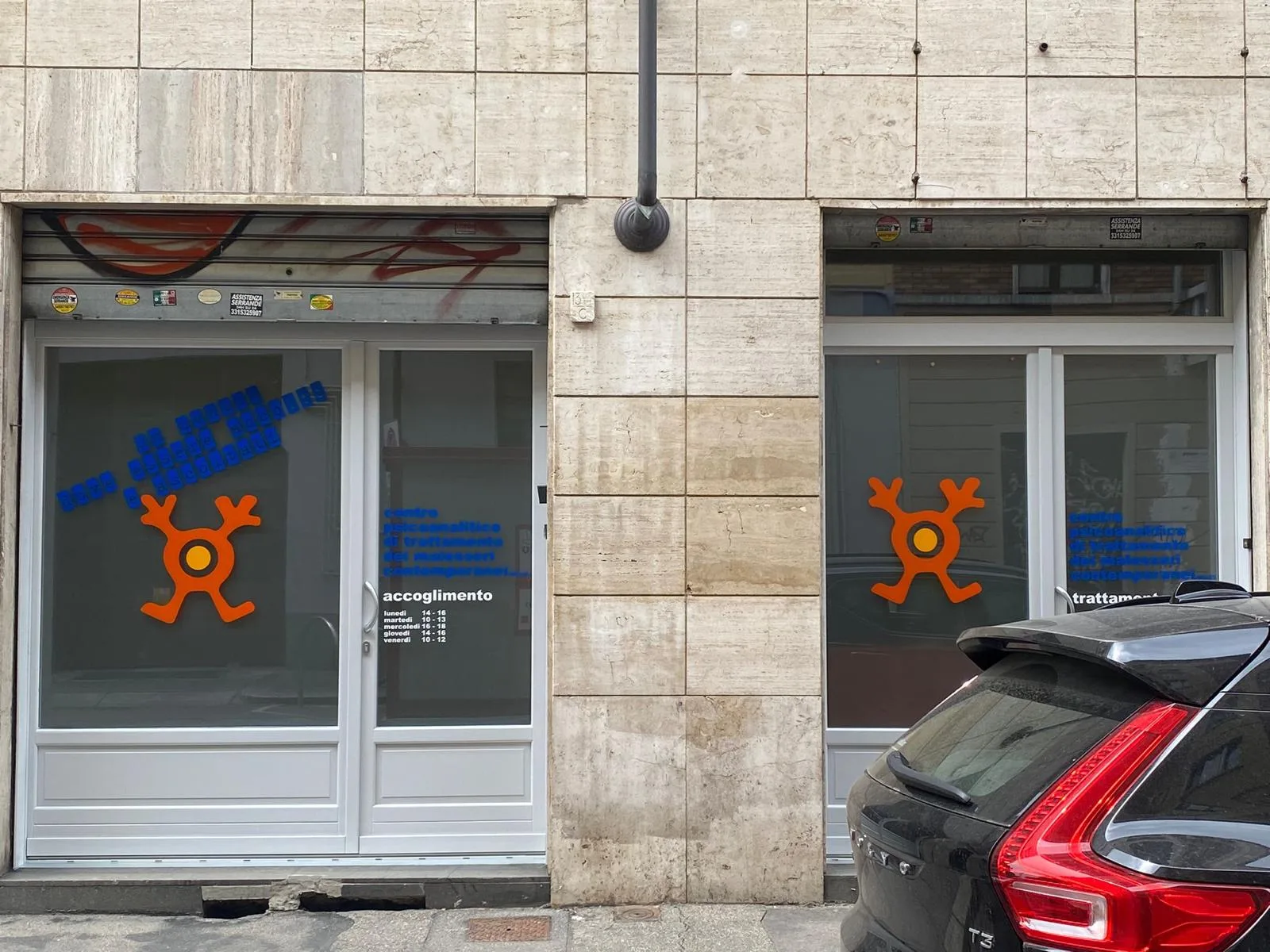 Vetrine di un centro con loghi arancioni e scritte blu in prespaziato applicati sul vetro