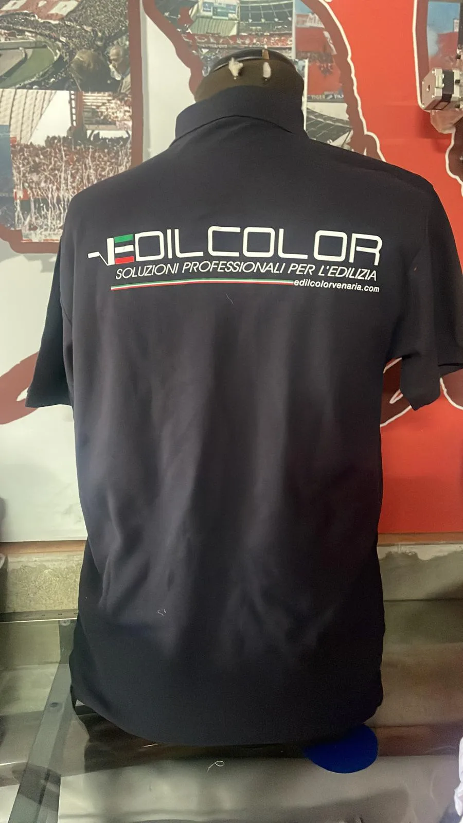 Retro di una polo blu scuro con logo e scritta di un'impresa edile stampati in bianco