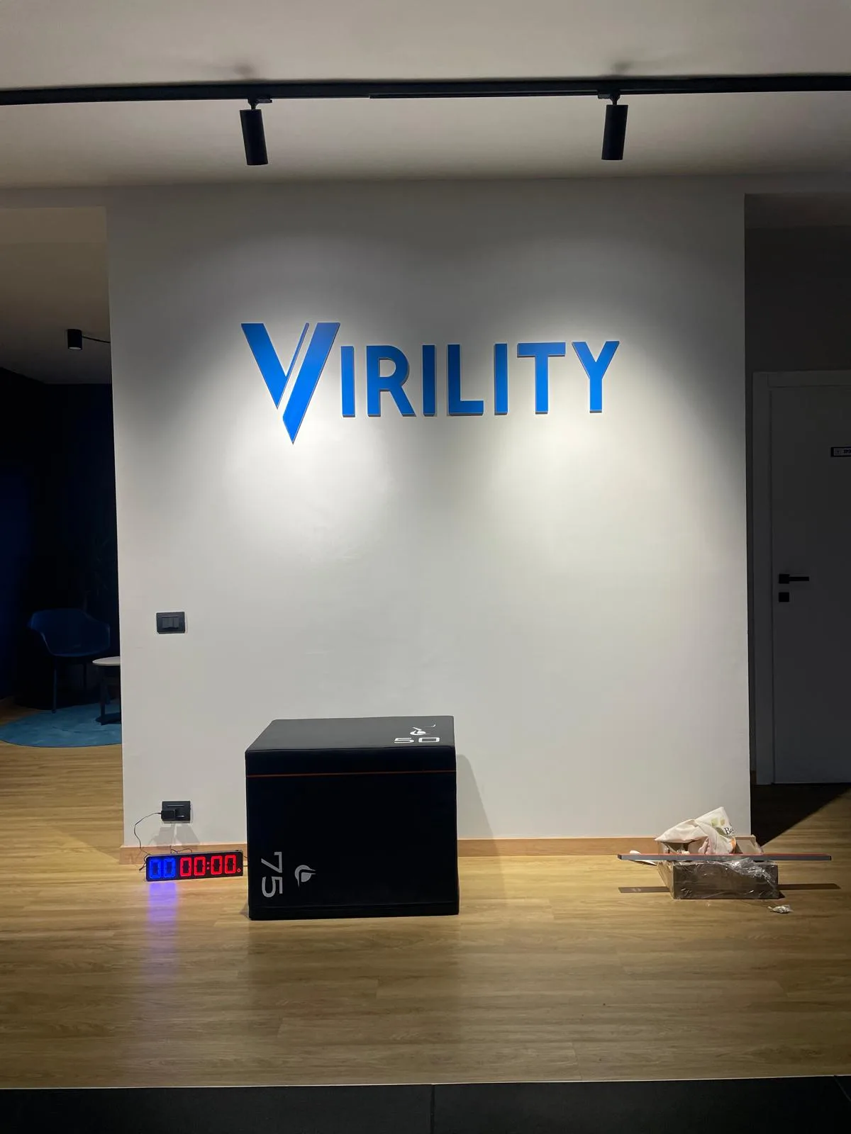 Logo blu a lettere in rilievo sulla parete della reception di una palestra