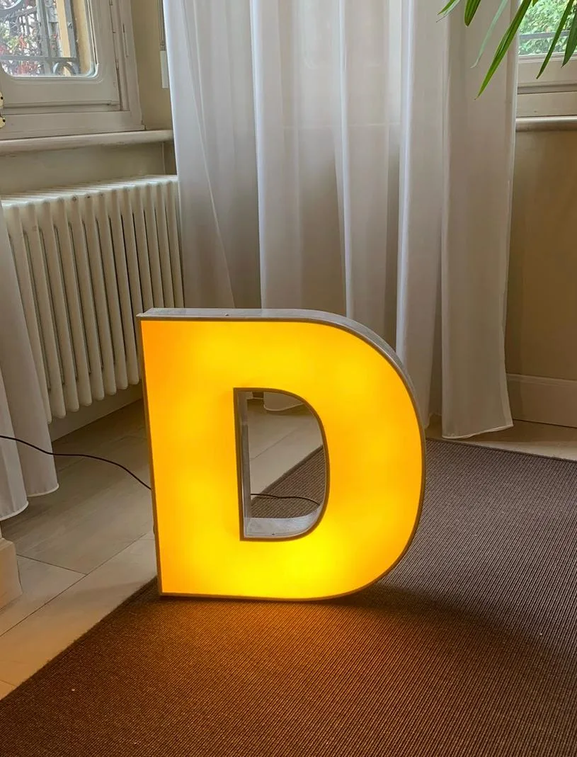 Lettera D luminosa gialla usata come lampada d'arredo in un soggiorno
