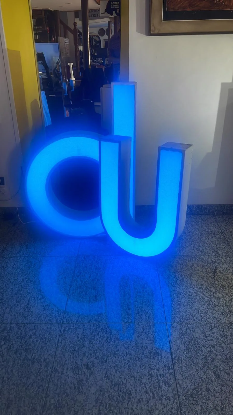 Lettere a e u luminose blu recuperate da una vecchia insegna, accese come oggetto d'arredo