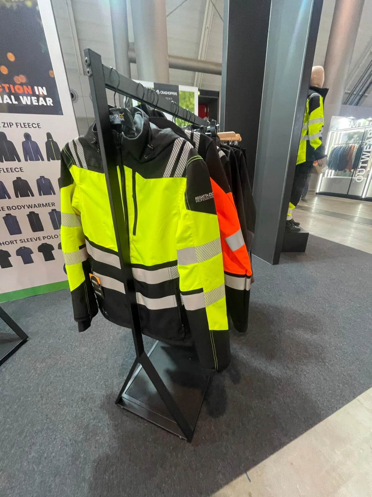 Giacca da lavoro gialla fluo e nera con bande riflettenti su un appendiabiti