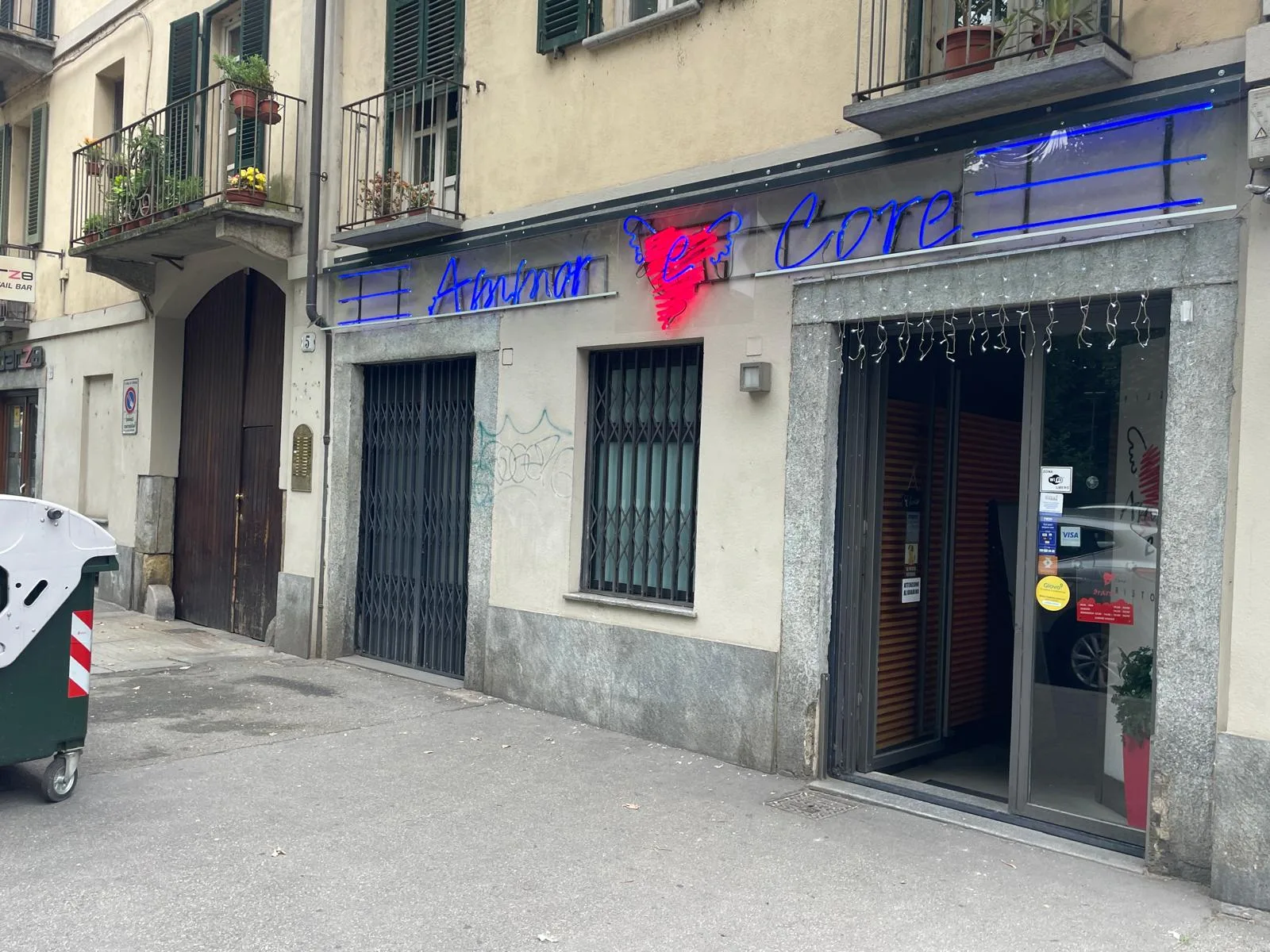 Insegna al neon blu e rossa sulla facciata di una pizzeria, di nuovo accesa dopo la riparazione