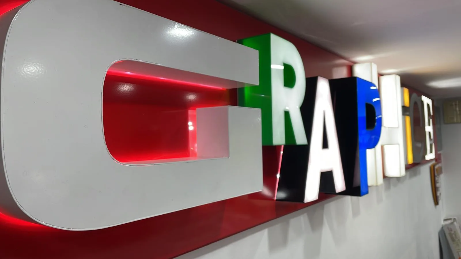 Insegna a lettere scatolate colorate e luminose su fondo rosso, rimessa a nuovo
