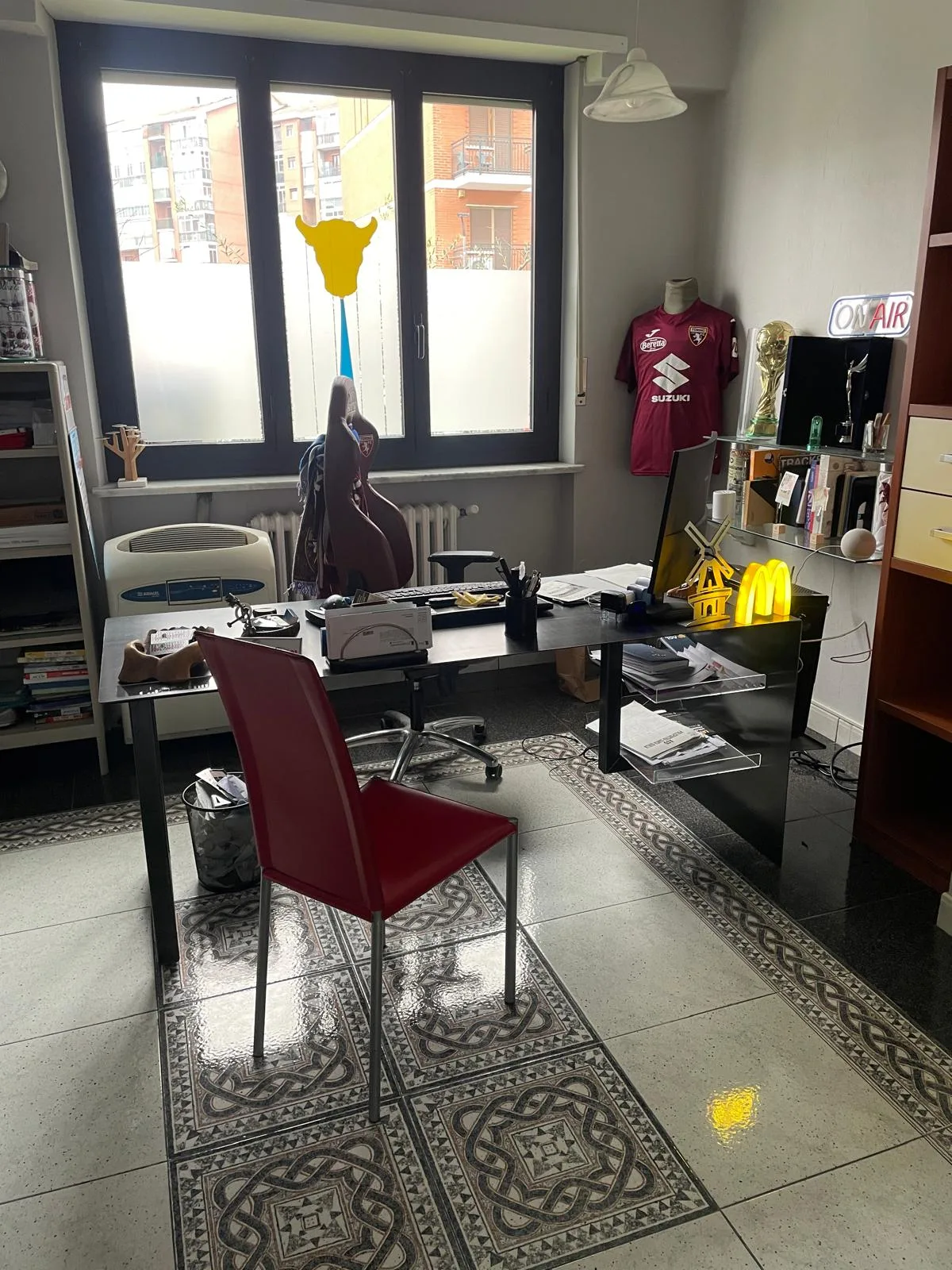 Lo studio di Che Stampa a Torino: scrivania con computer, maglia del Torino appesa e insegne luminose d'arredo